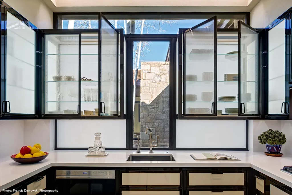 Steel windows act as a wall behind glass cabinets to let light flow in