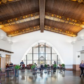 People seated and walking in airport, large arched interior steel window, located in Santa Barbara, CA.